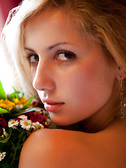 Amazing teen honey in tempting black stockings posing on bed with a bouquet of flowers.